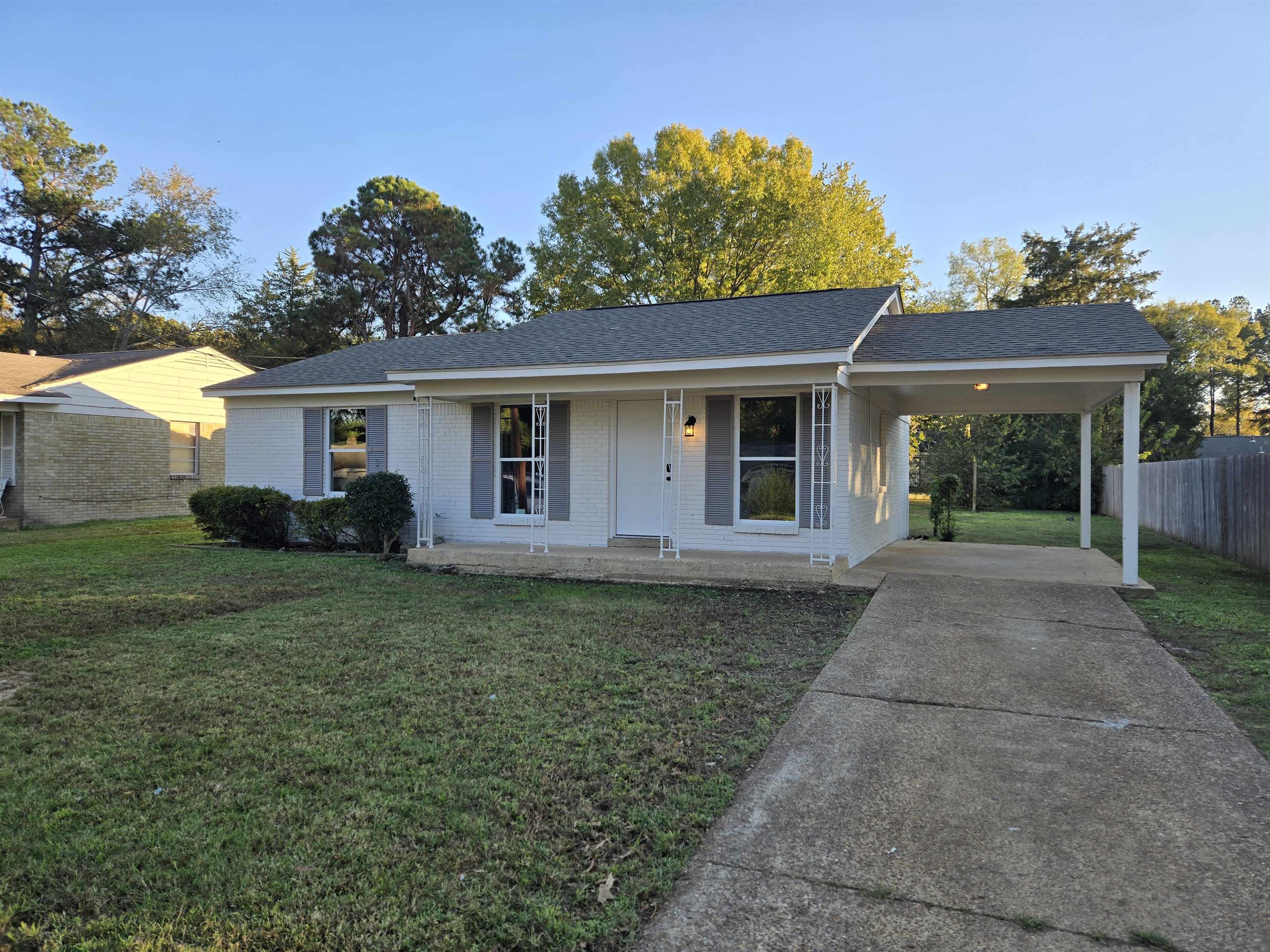 Ranch-style home with a front lawn, a porch, and a carport