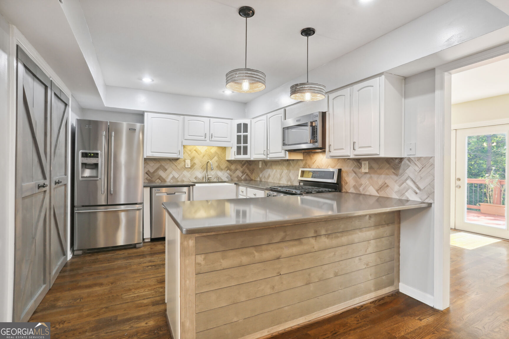 a kitchen with kitchen island white cabinets and stainless steel appliances