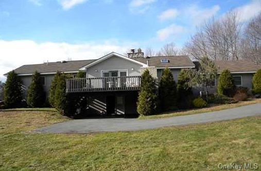 View of front facade with a front lawn and a wooden deck