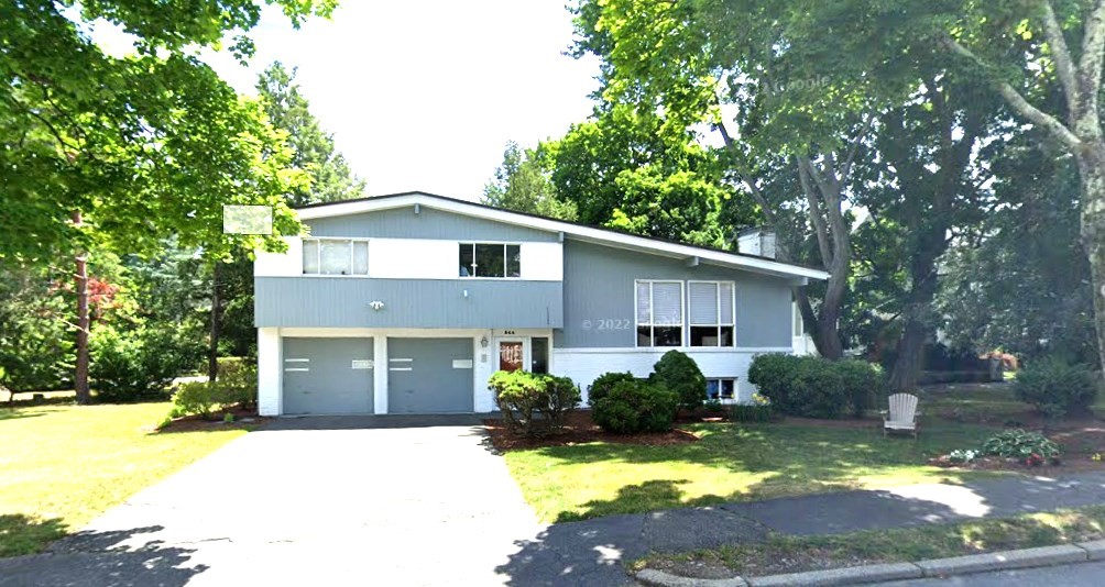 a front view of house with yard and trees in the background