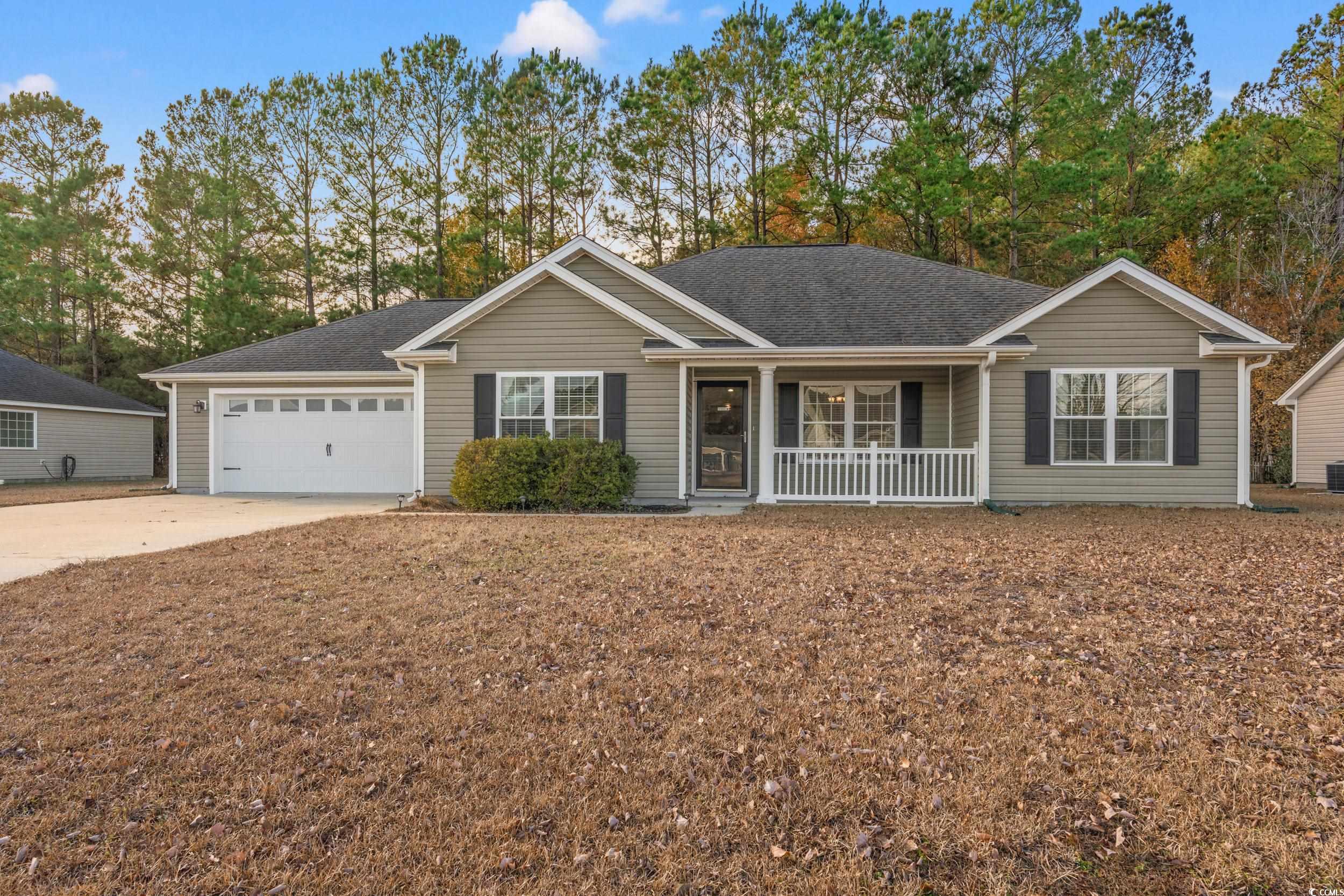 Ranch-style home featuring covered porch and a gar