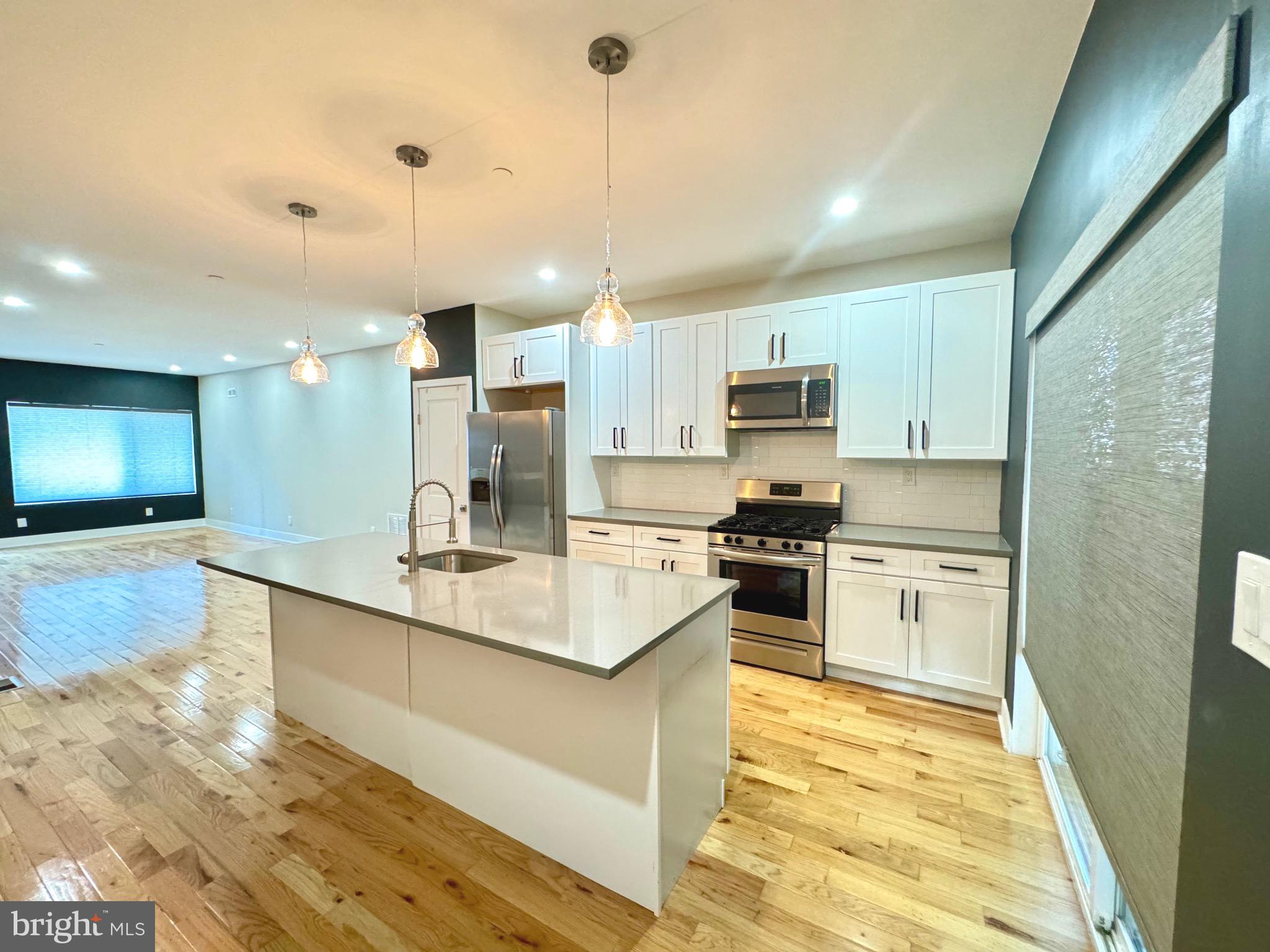 a large kitchen with kitchen island a sink stainless steel appliances and cabinets