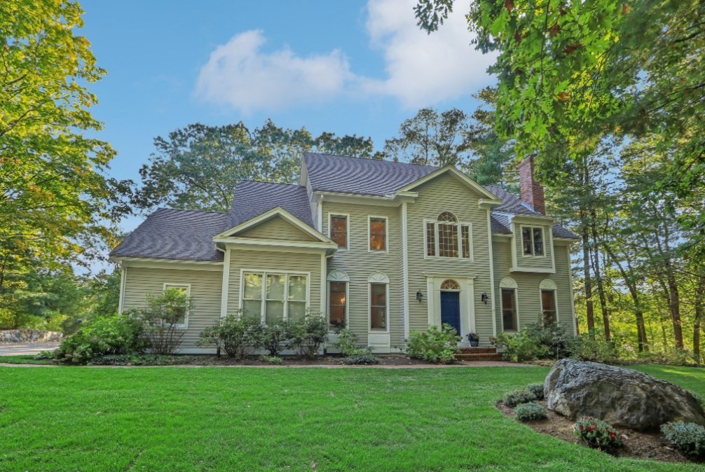 a front view of a house with a garden and trees