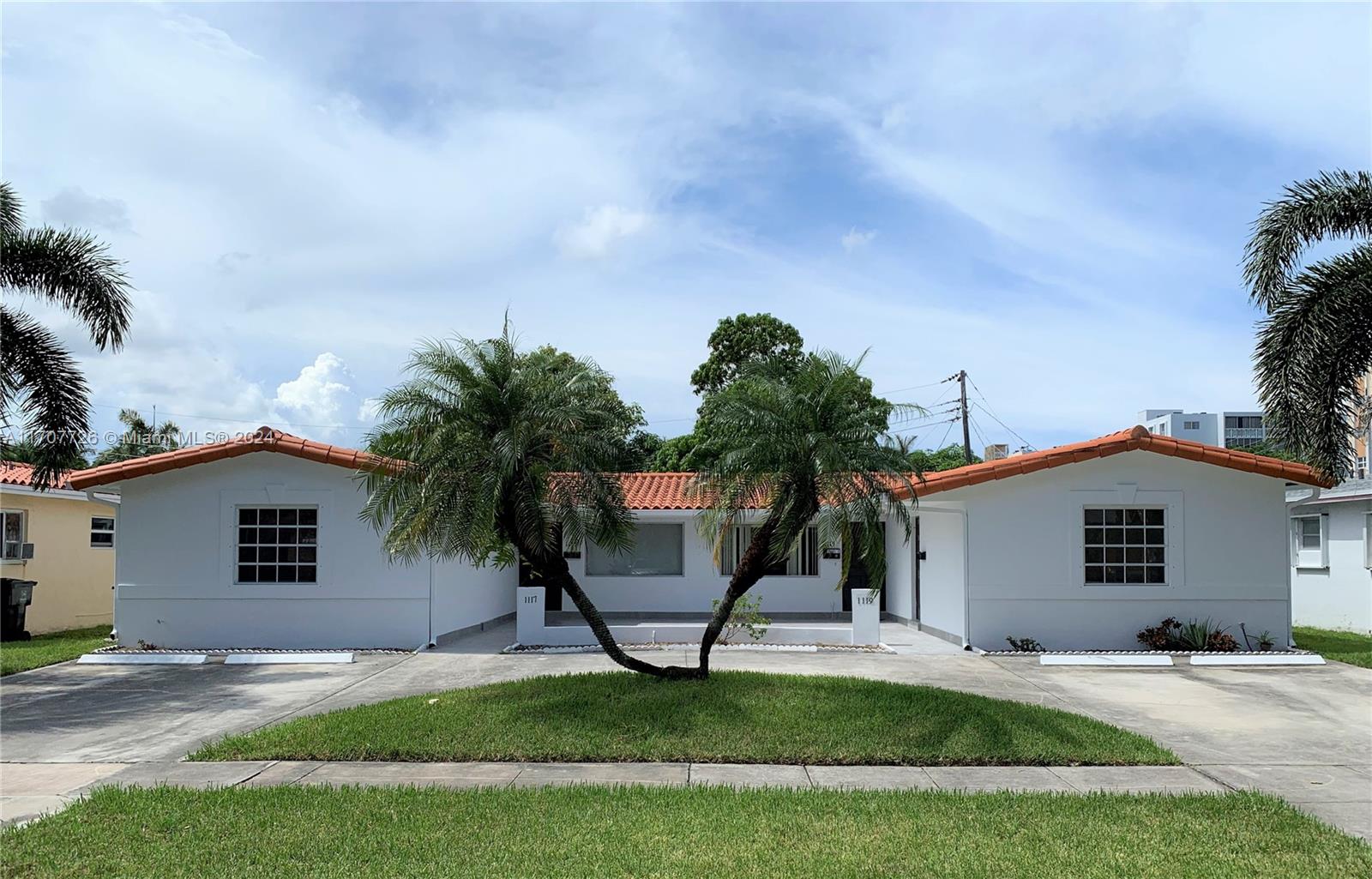 a view of a house with a yard and palm trees