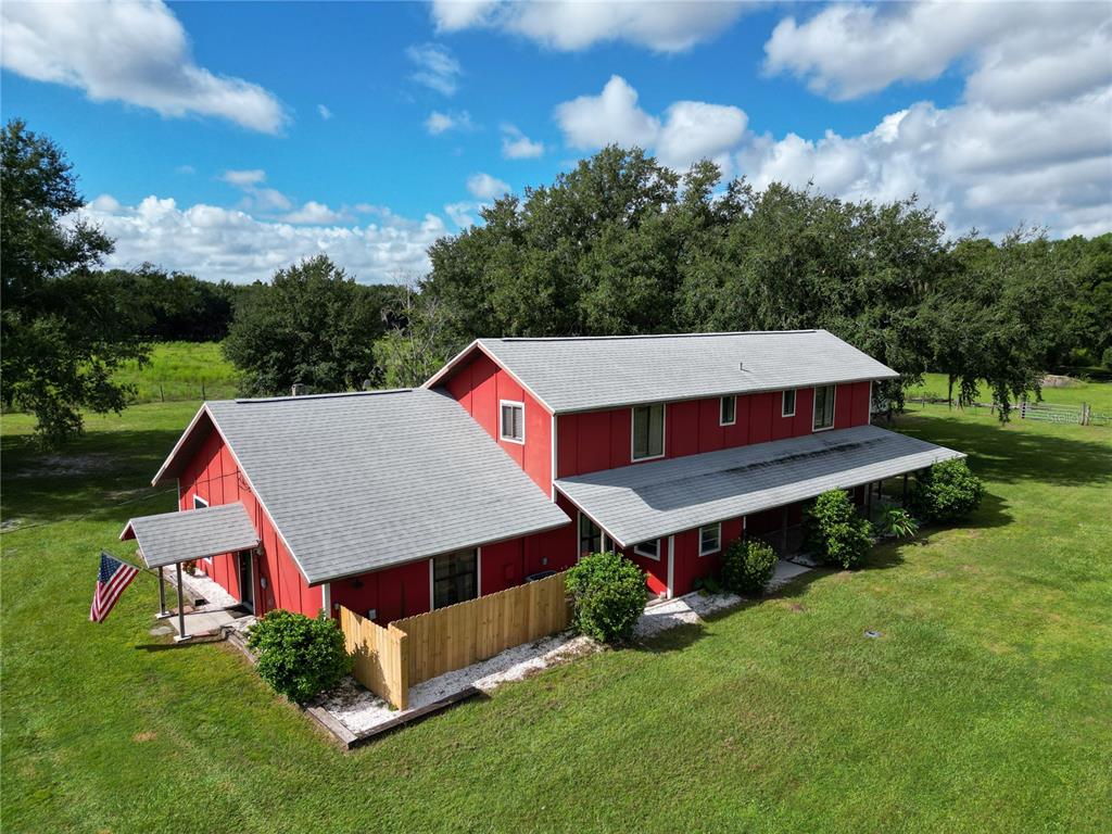 an aerial view of a house sitting in a big yard with large trees