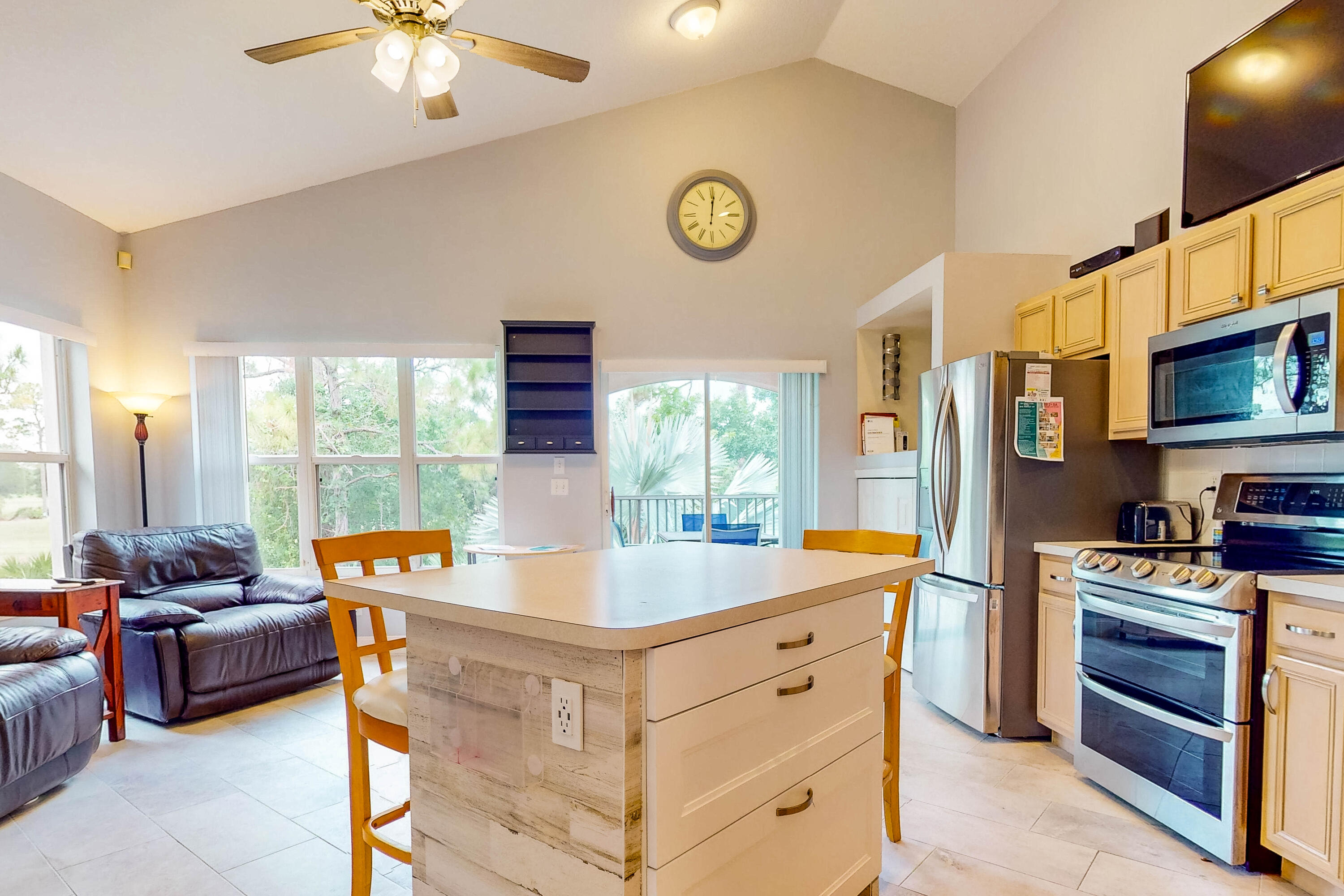 a living room with stainless steel appliances granite countertop furniture and a flat screen tv