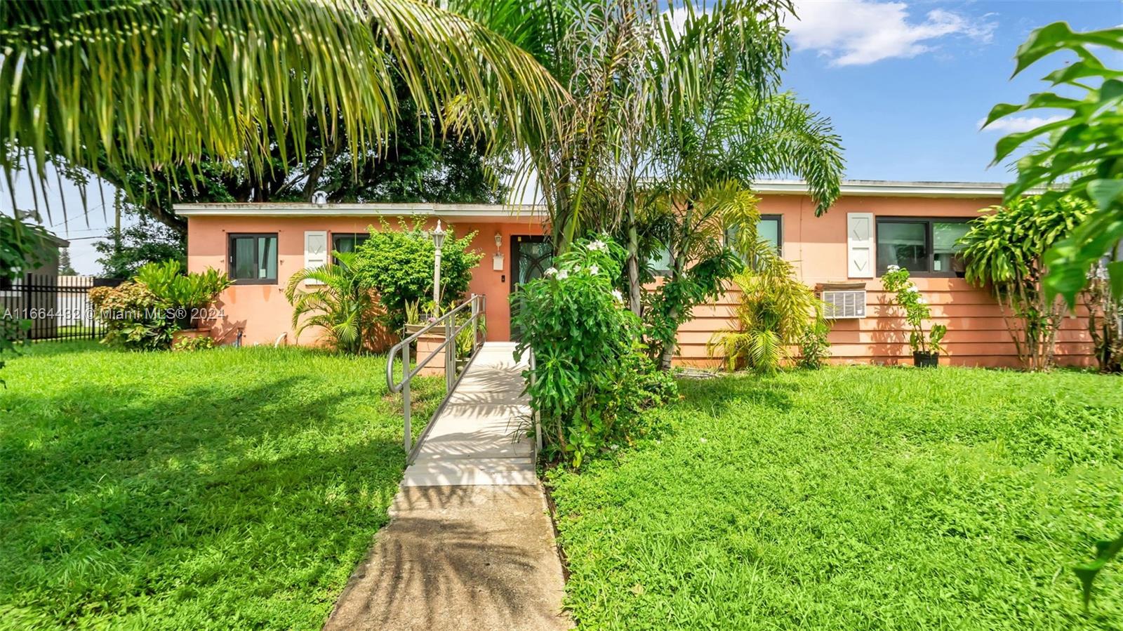 a front view of a house with a yard and potted plants