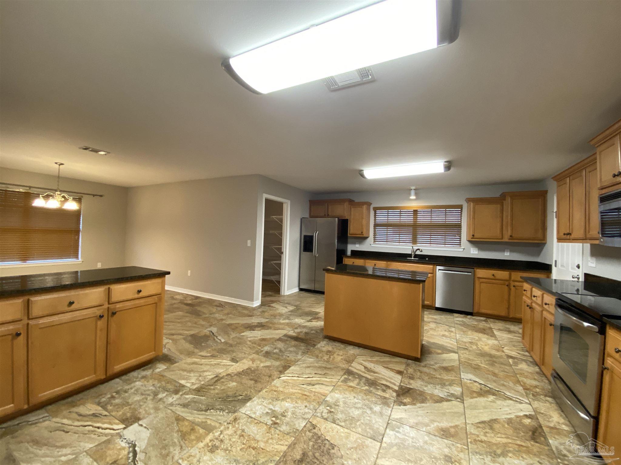 a large kitchen with stainless steel appliances granite countertop a sink and counter space