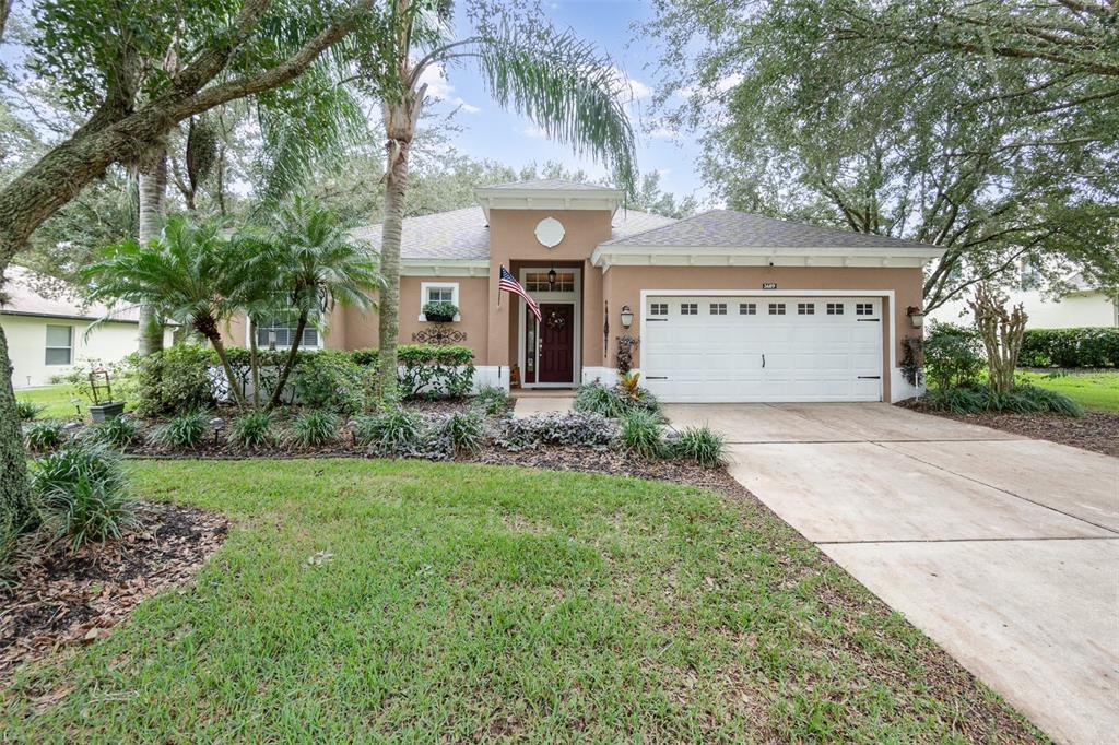 front view of house with a yard and trees all around