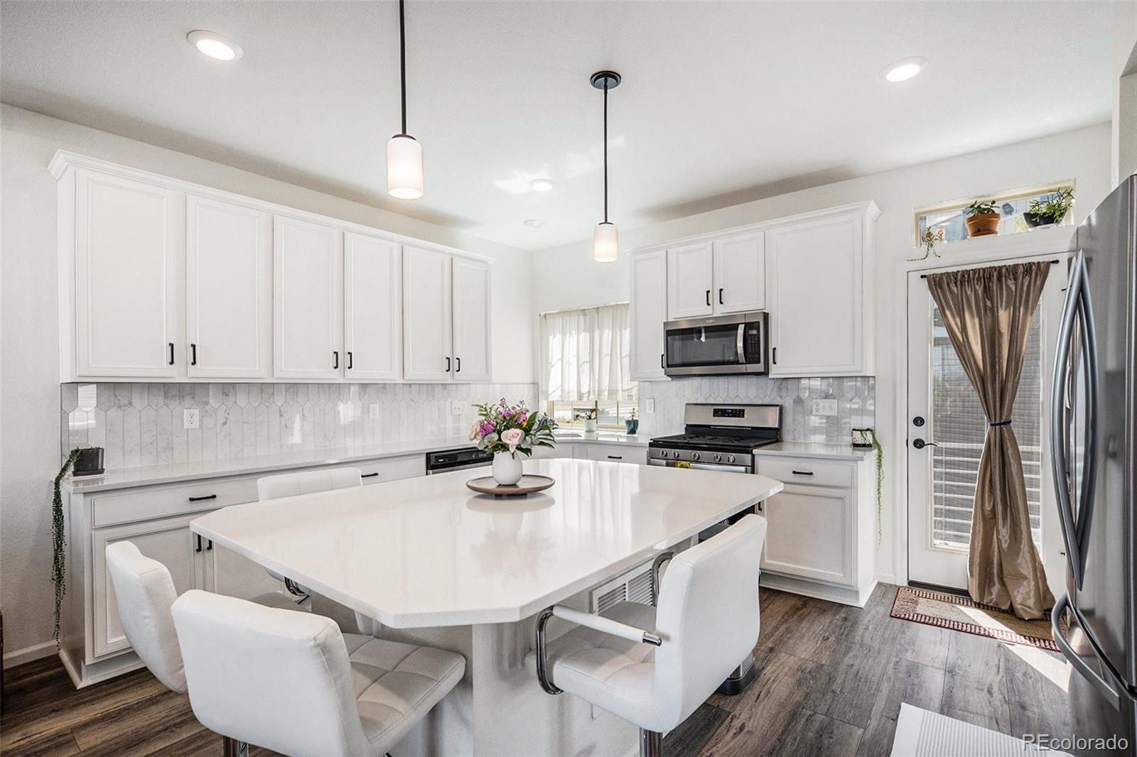 a kitchen with a white center island and stainless steel appliances