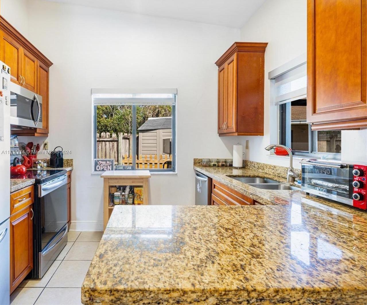 a kitchen with stainless steel appliances granite countertop a stove top oven a sink a counter space and cabinets