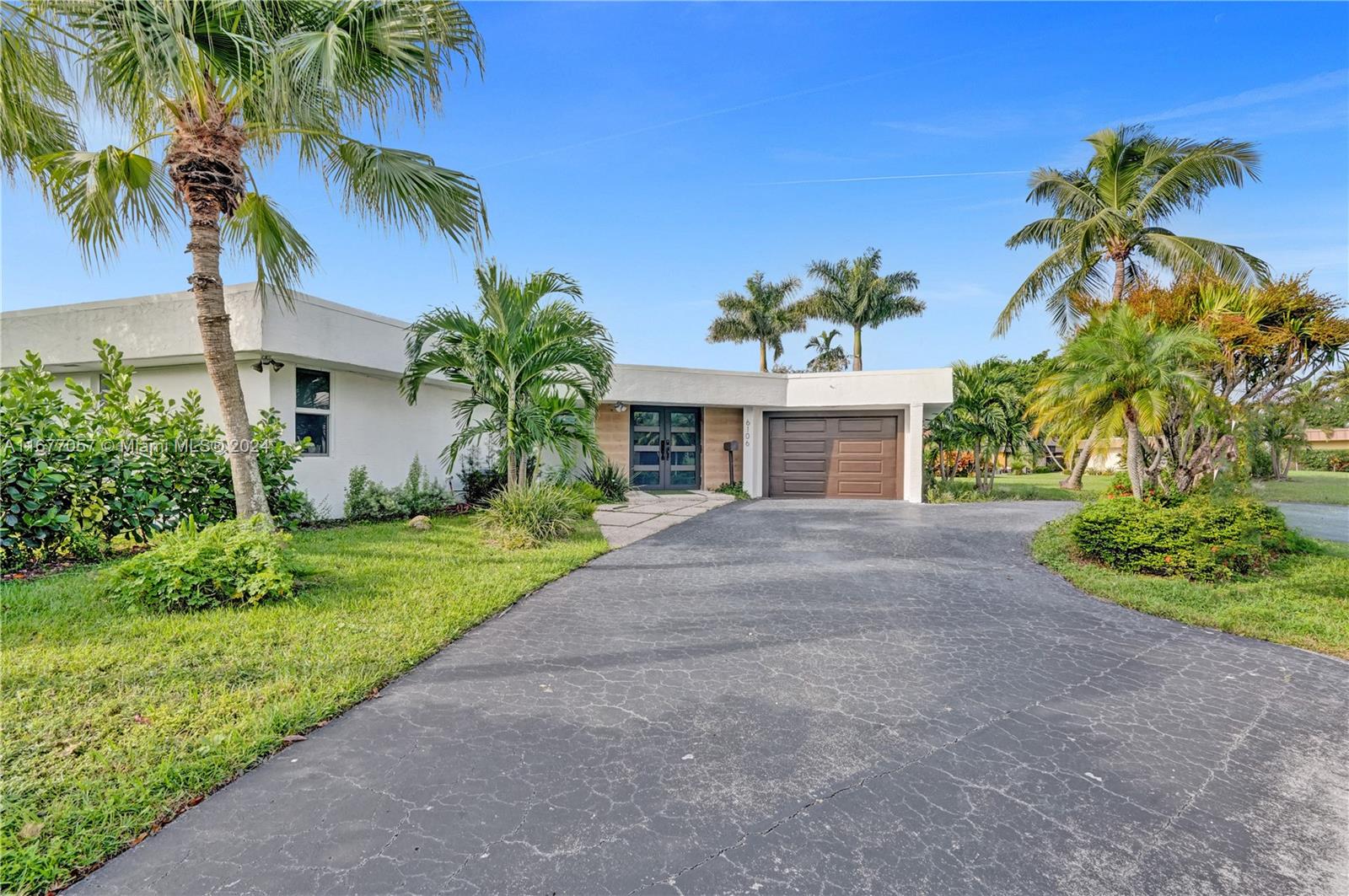 a view of a house with a yard and palm trees