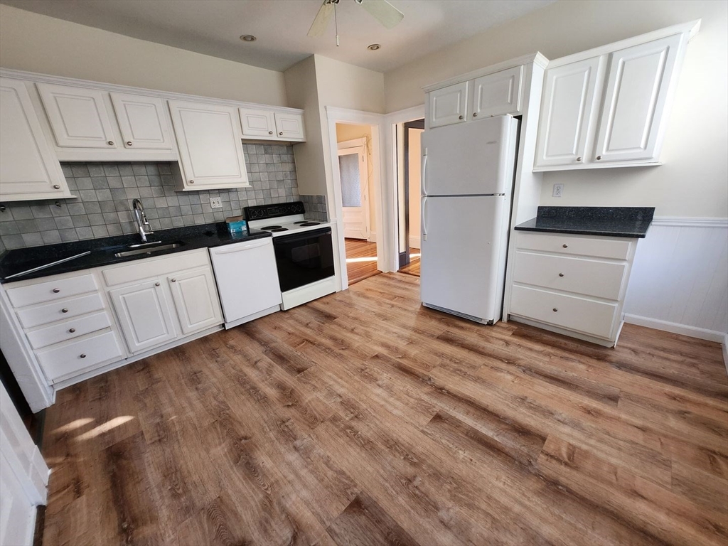 a kitchen with granite countertop white cabinets and refrigerator