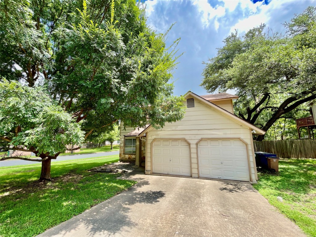 a view of a house with a yard and large tree