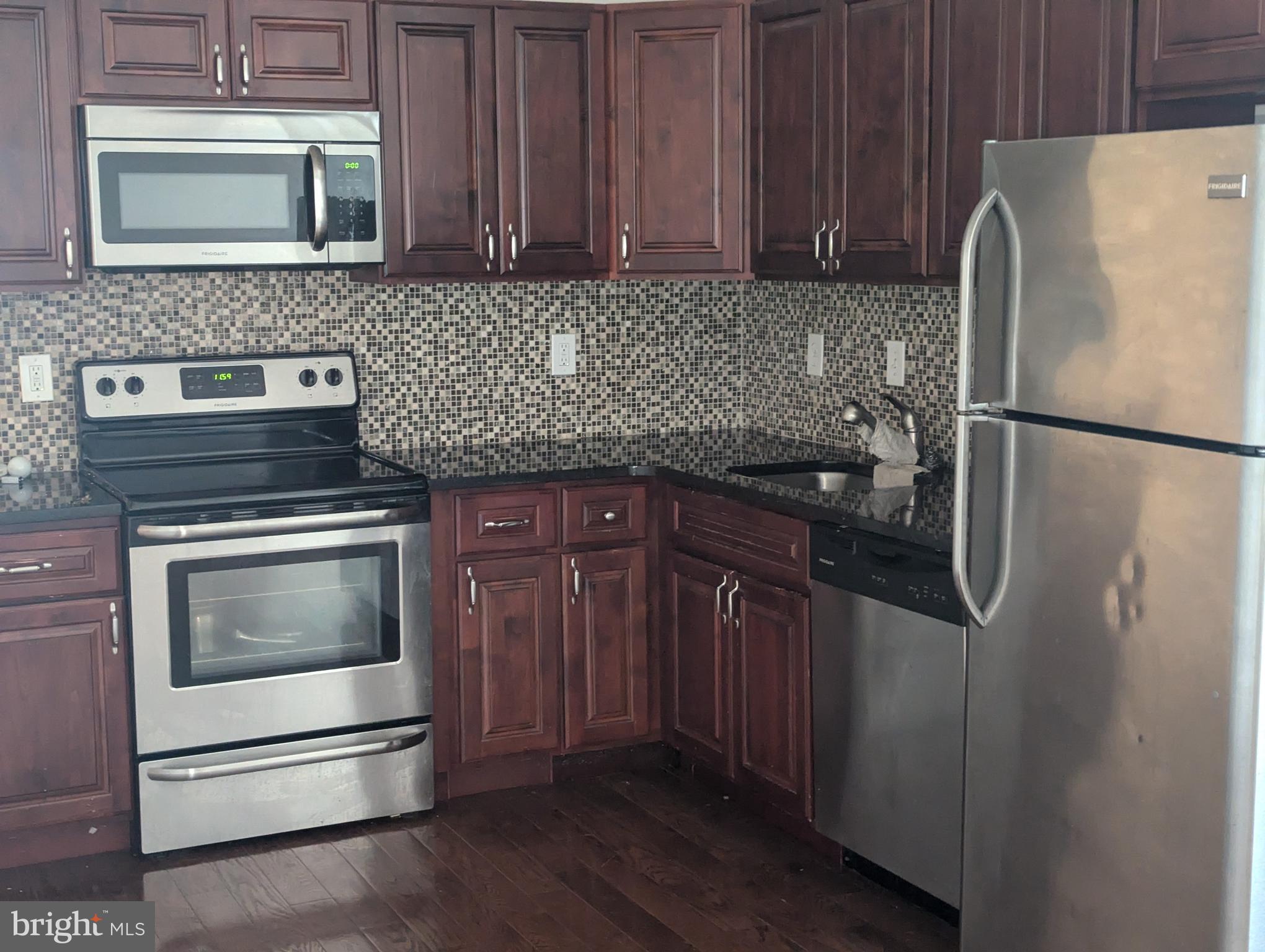 a kitchen with granite countertop a refrigerator stove and microwave