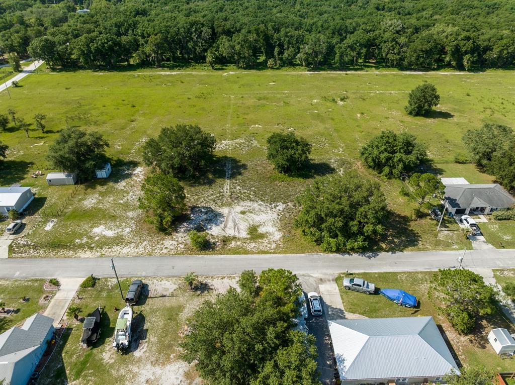 an aerial view of ocean with residential house outdoor space and trees all around