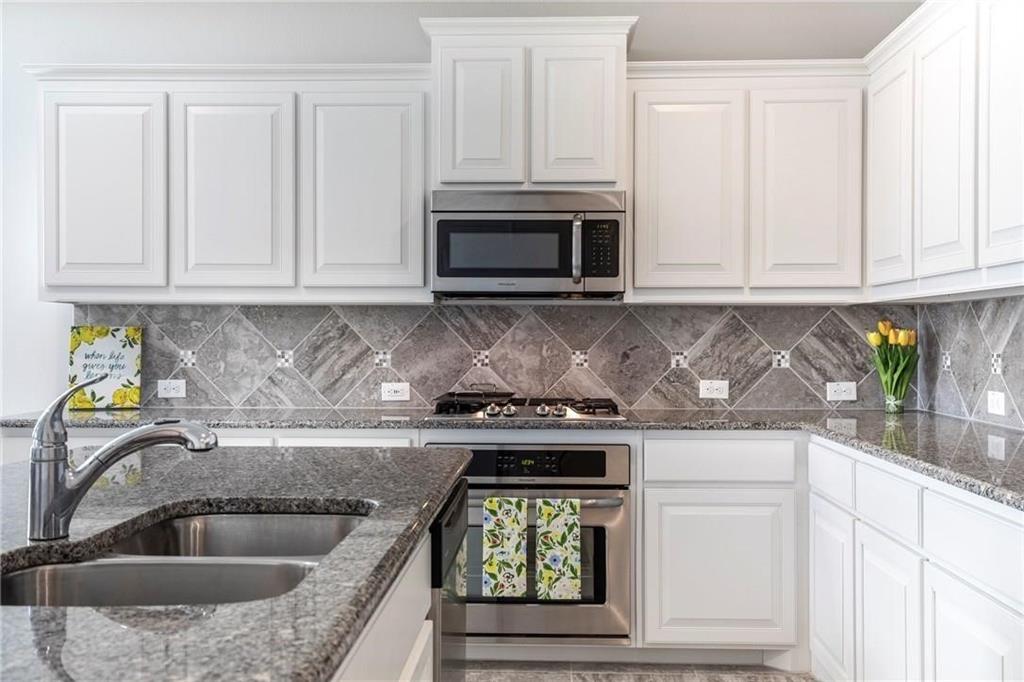 a kitchen with granite countertop white cabinets stainless steel appliances and a sink