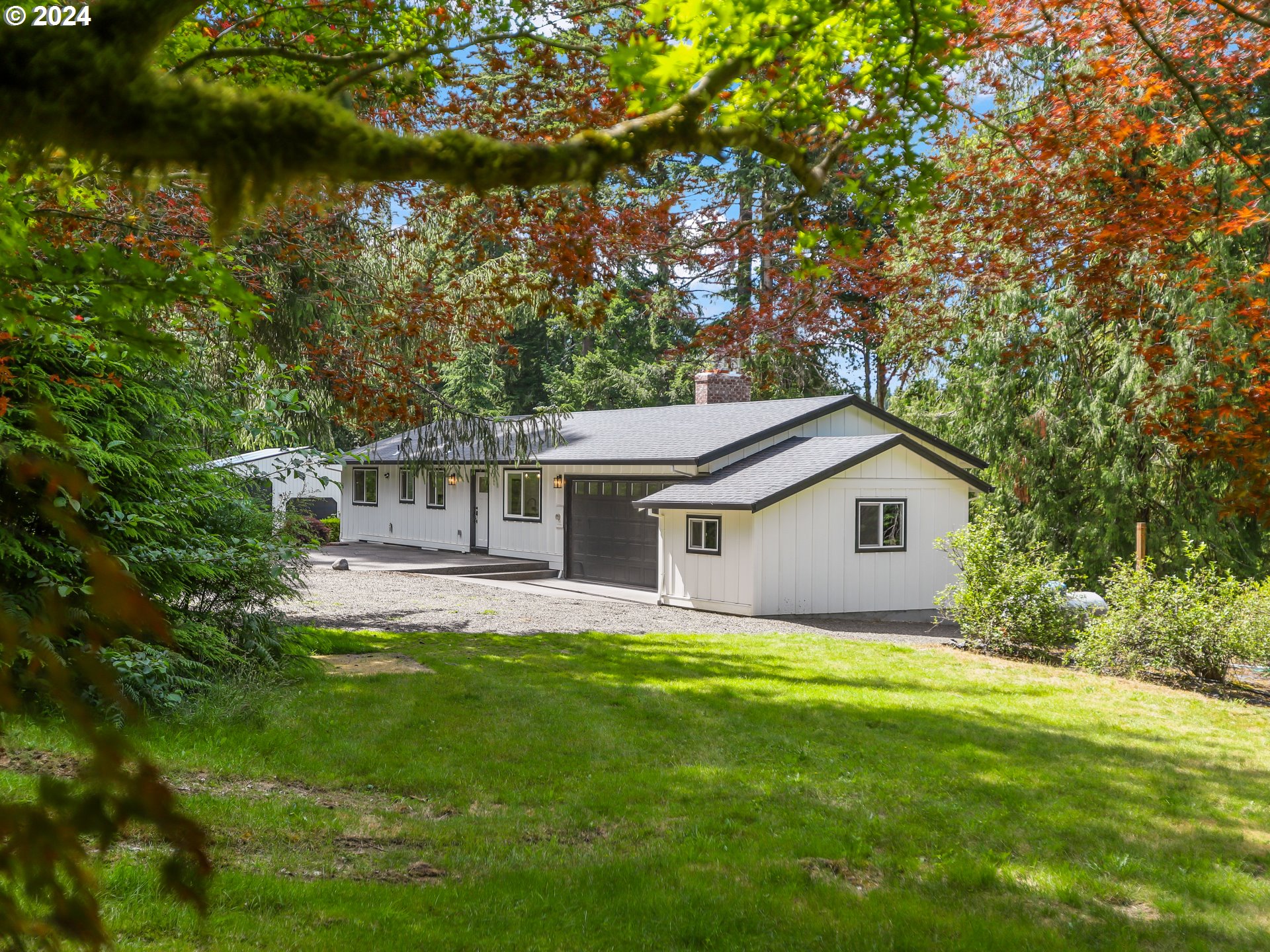 a house that is sitting in the grass with large trees