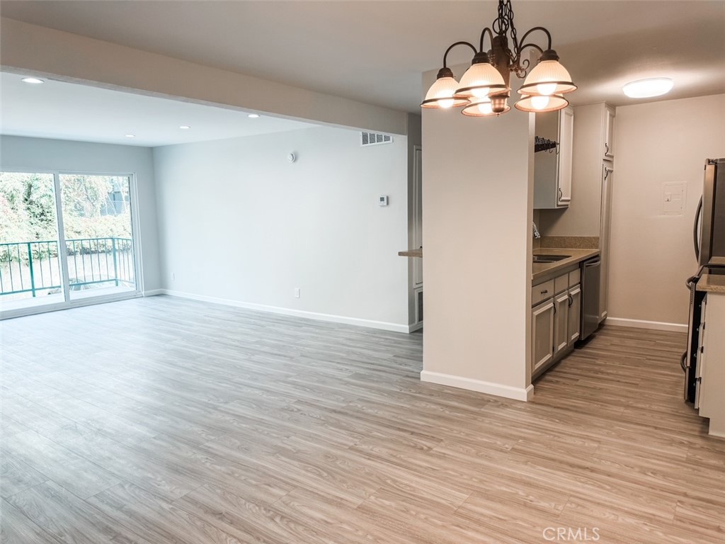 a view of a kitchen with stainless steel appliances wooden floor and large windows