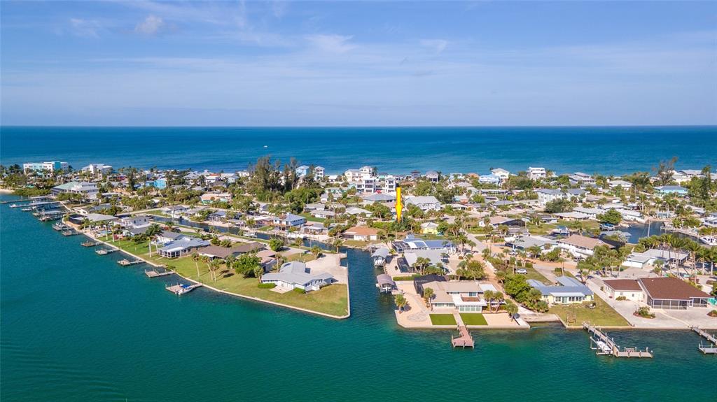 an aerial view of ocean and residential houses with outdoor space