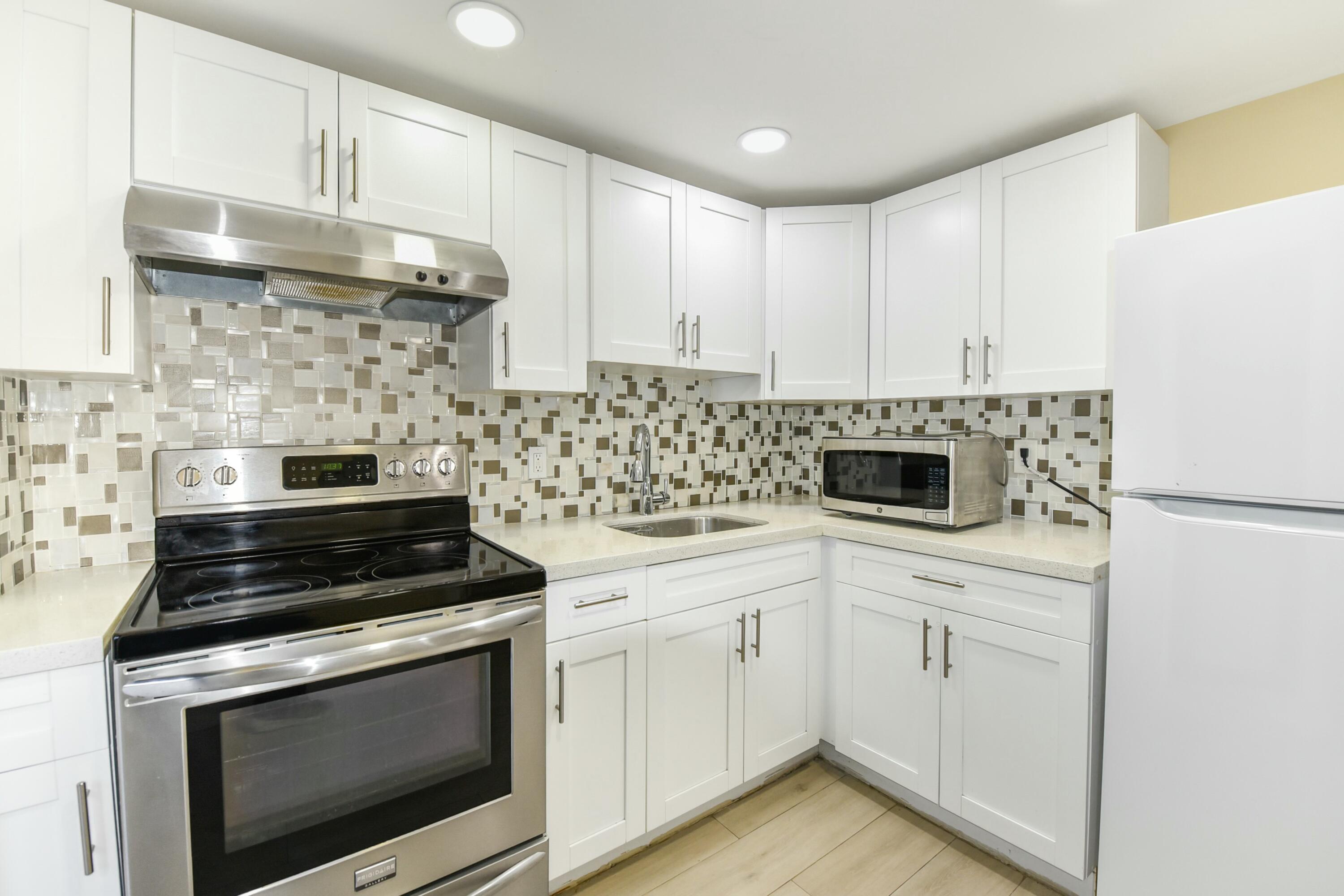 a kitchen with white cabinets and appliances