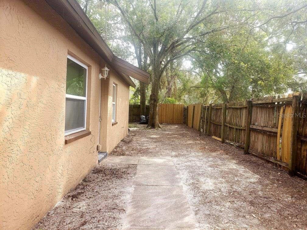 a view of backyard with wooden fence and large trees