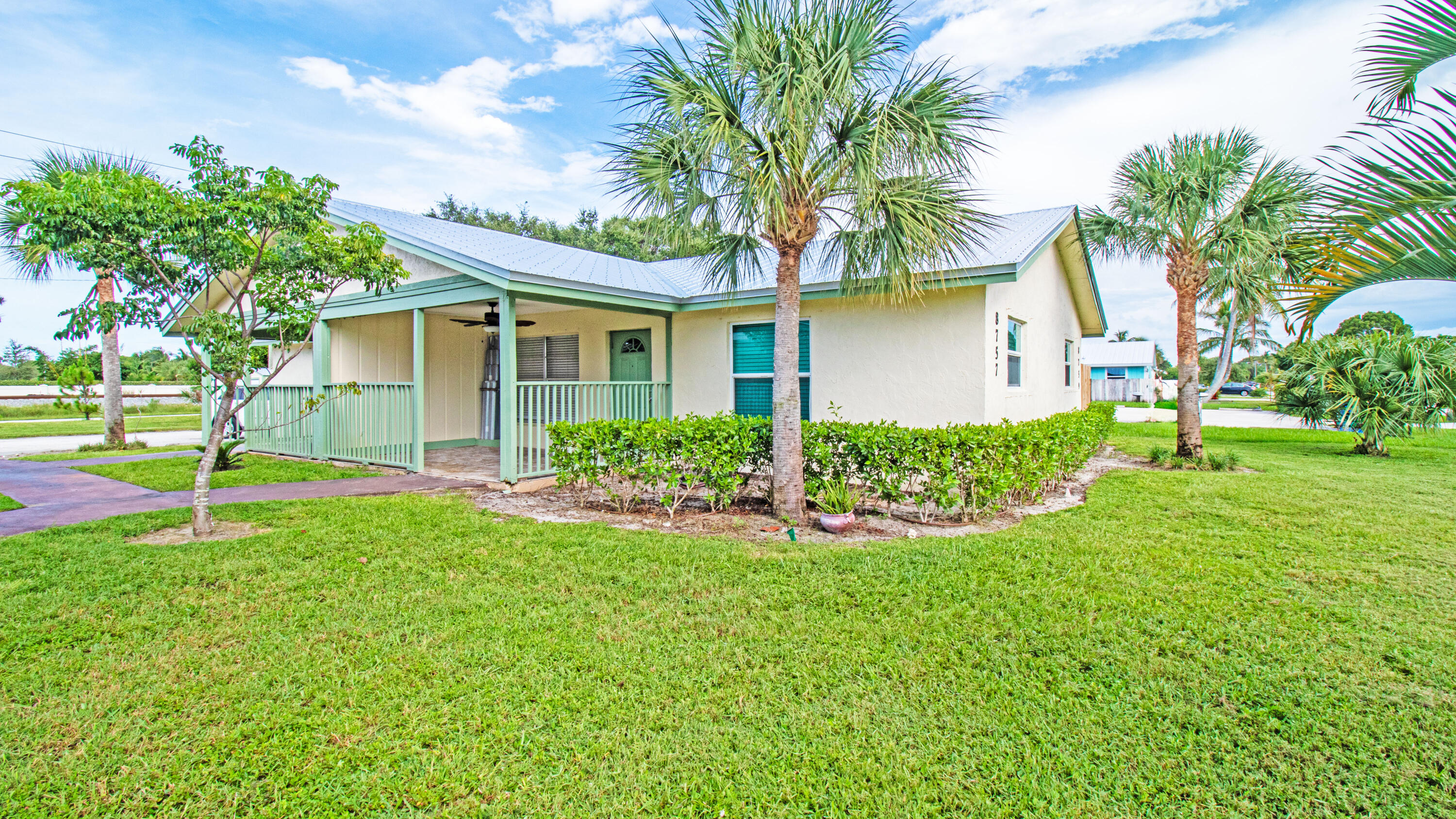 a front view of a house with a yard and palm trees