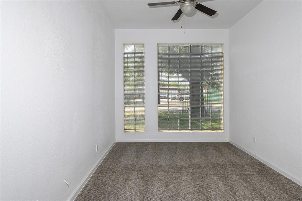 an empty room with chandelier fan and windows