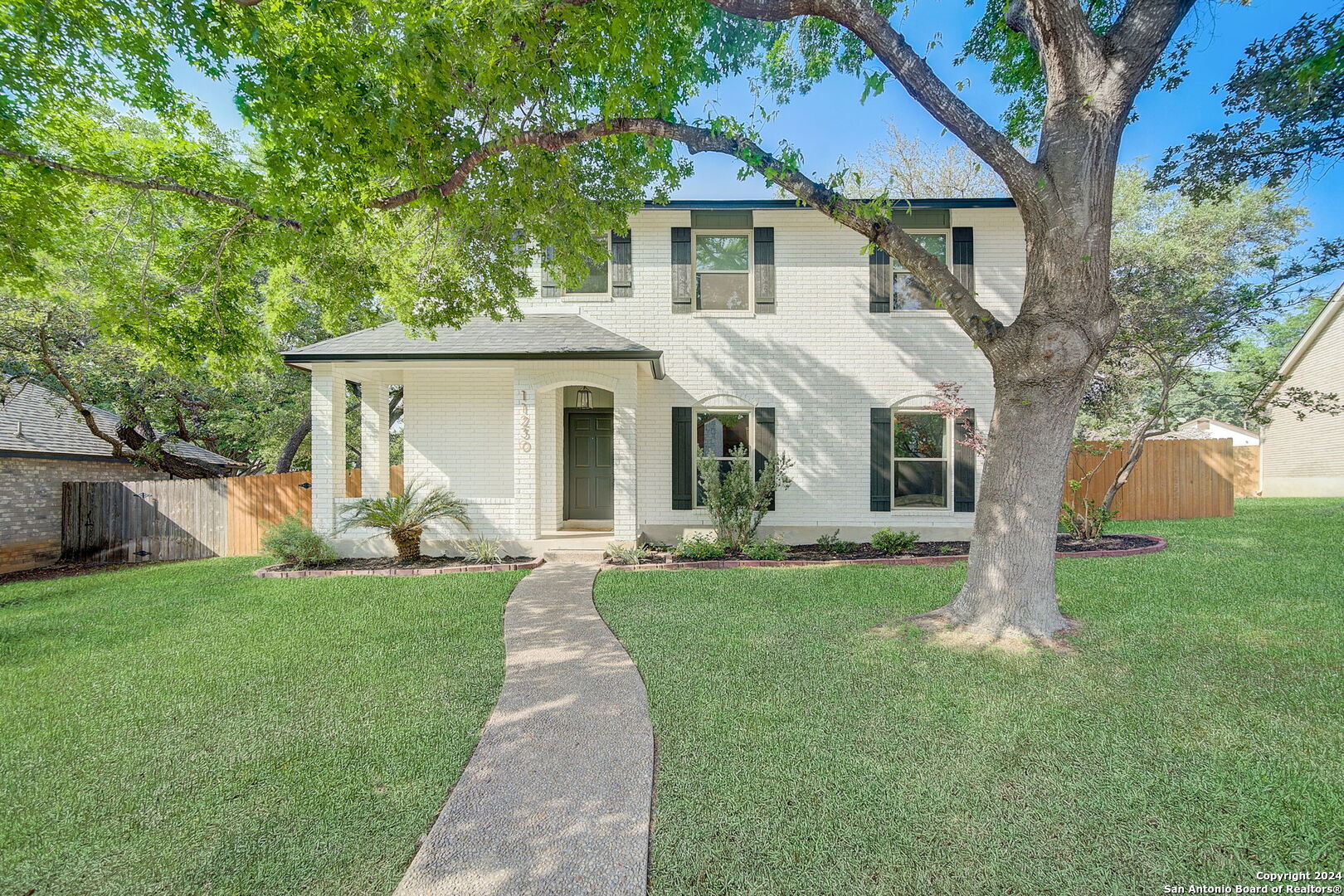 a front view of a house with a yard and trees