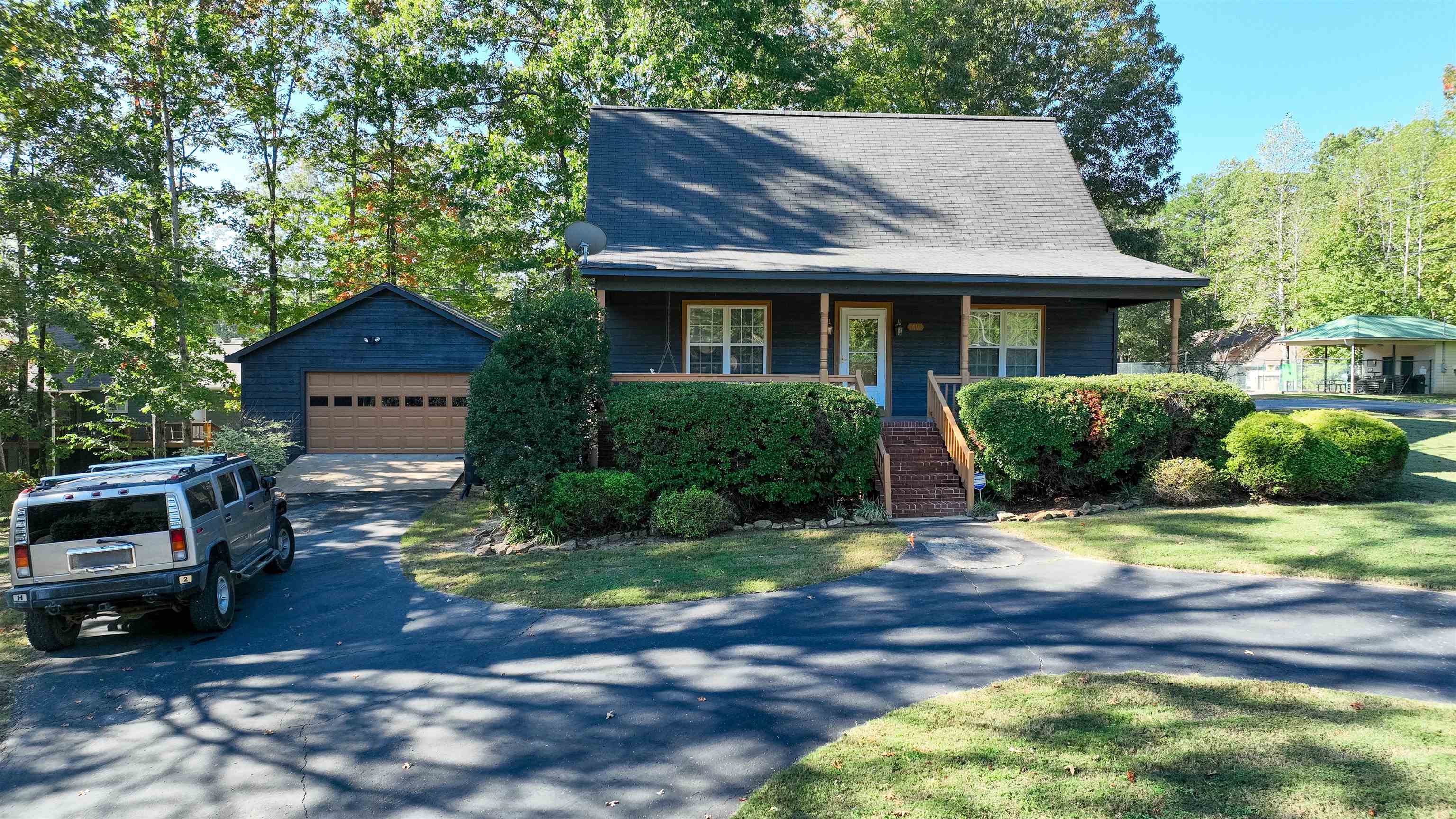 View of front of house with an outdoor structure, a garage, a front lawn, and a porch