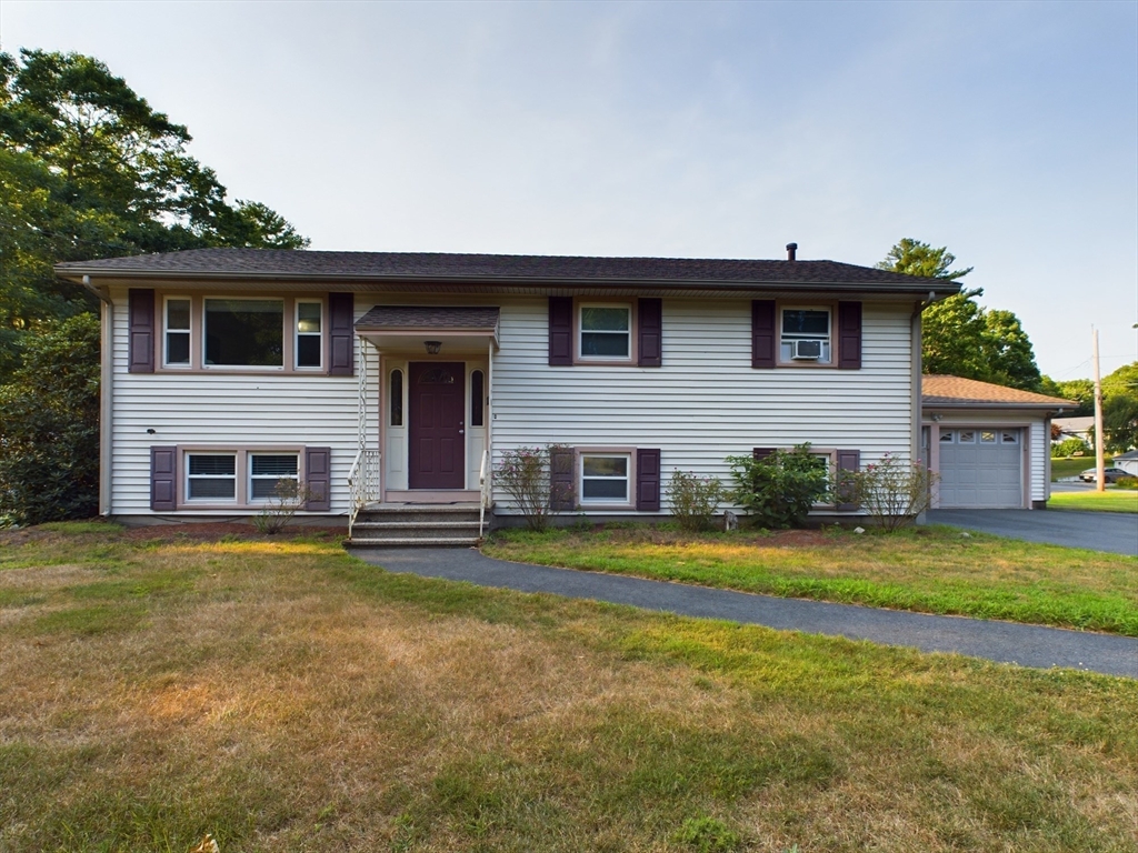 a front view of house with yard and trees in the background