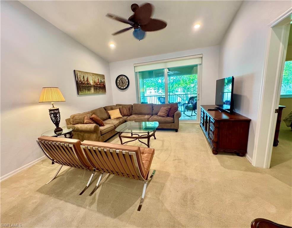 Living room featuring ceiling fan, light carpet, and vaulted ceiling