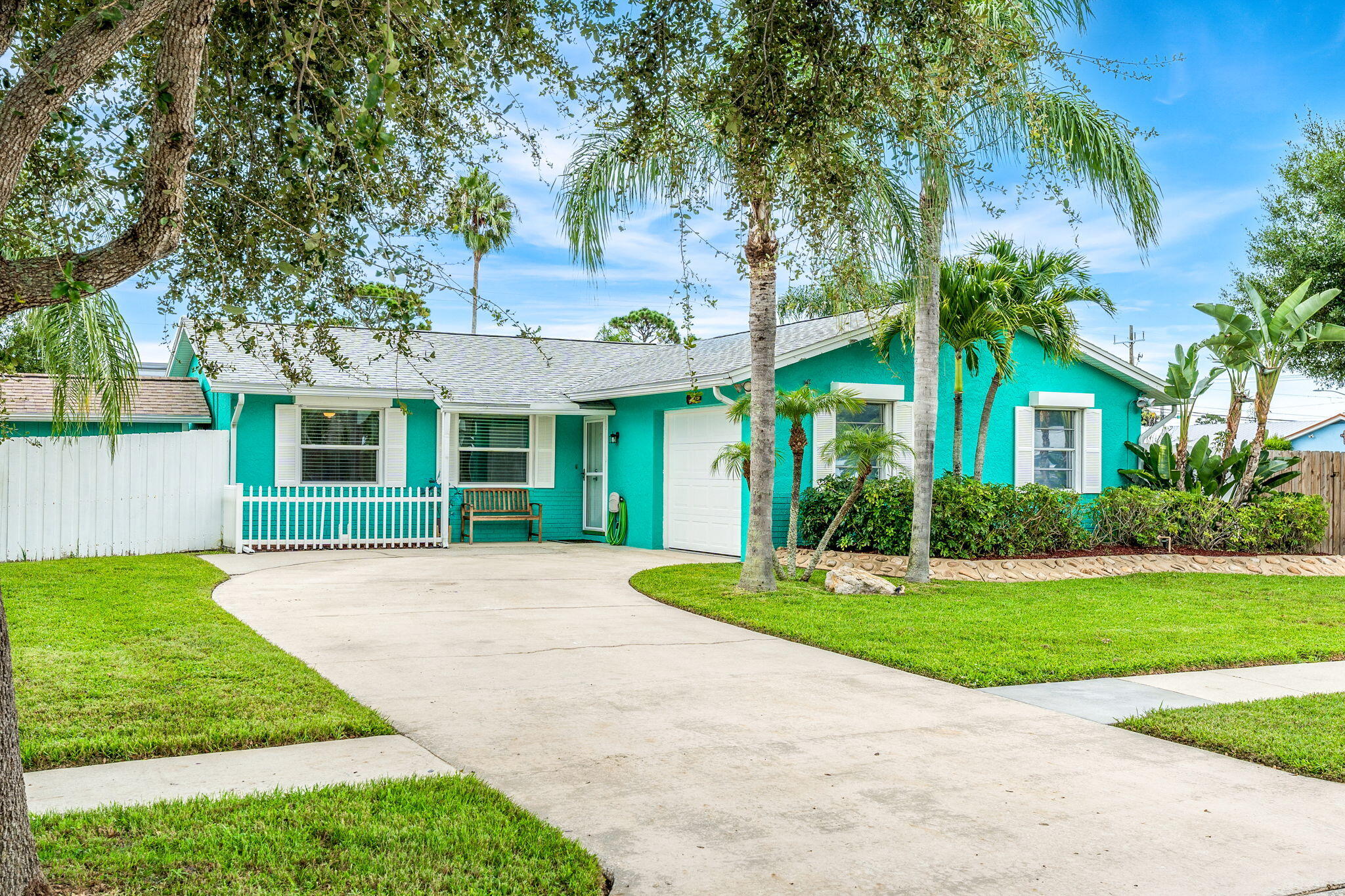 a view of a house with a yard and palm trees