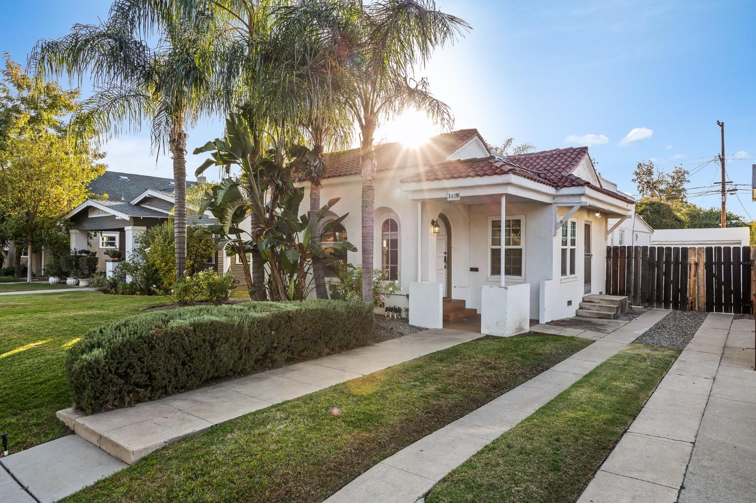 a view of a white house next to a yard with palm trees