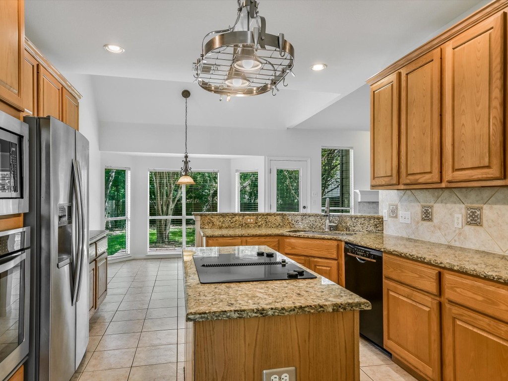 a kitchen with stainless steel appliances granite countertop a sink a stove and a refrigerator