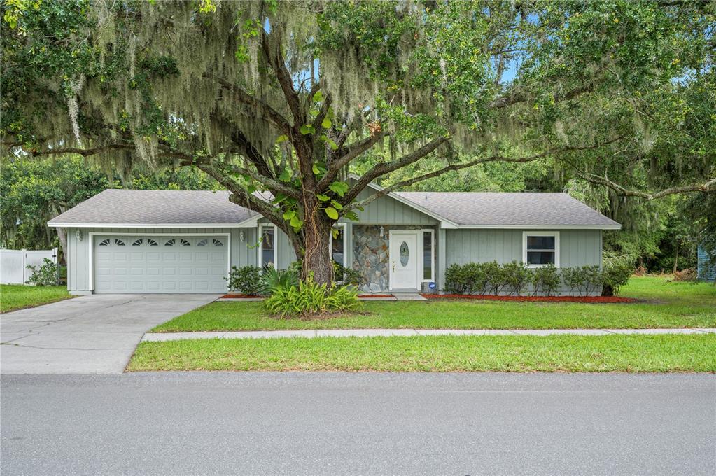 a front view of a house with a garden and trees