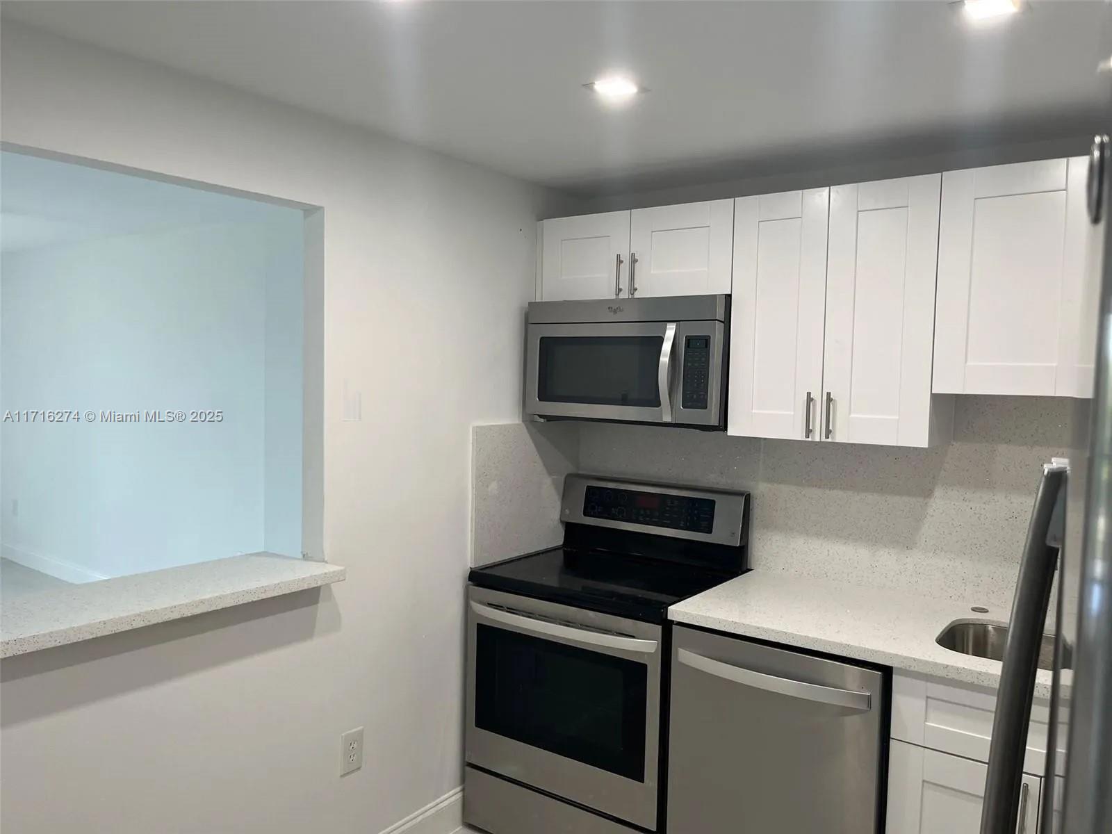 a view of kitchen with microwave and cabinets