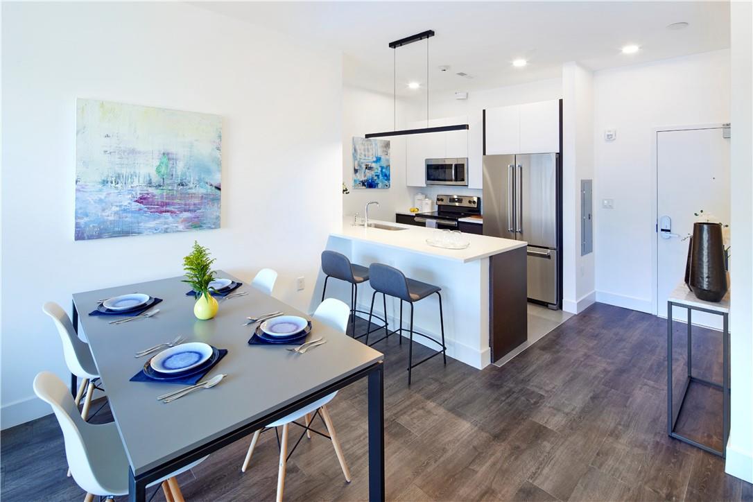 a kitchen with stainless steel appliances granite countertop a dining table chairs and a refrigerator