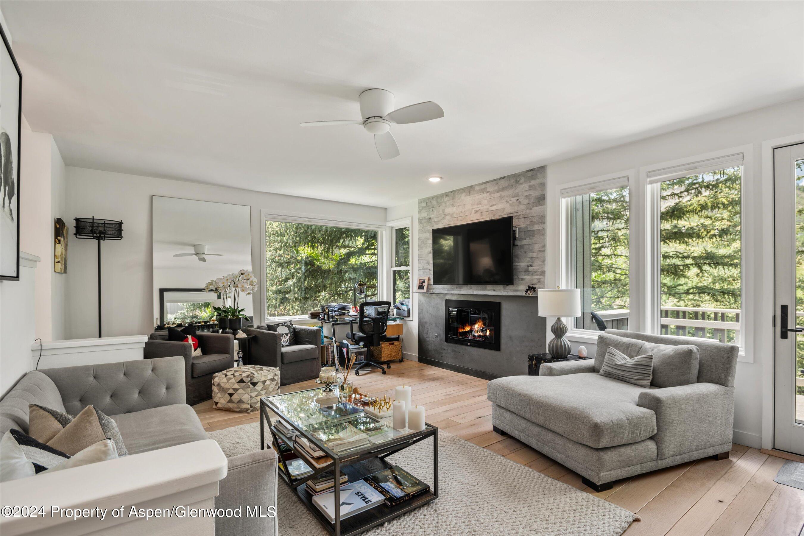 a living room with furniture a fireplace a large window and a flat screen tv