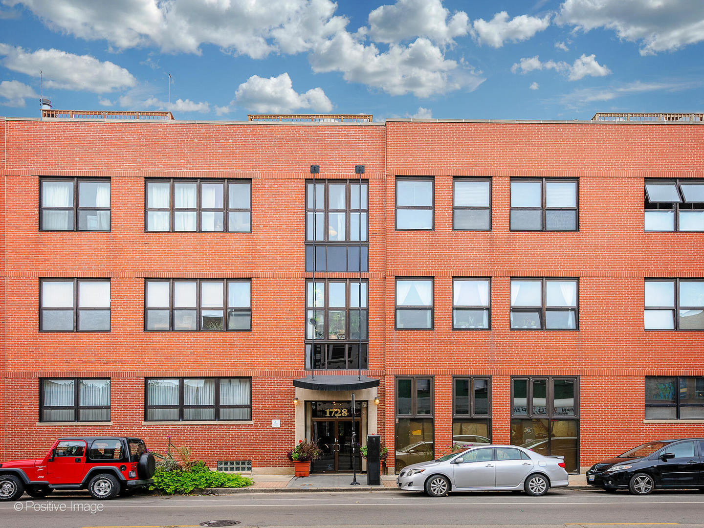 a front view of a building with lots of windows and trees