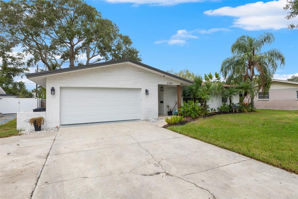 a view of a house with a yard and palm trees