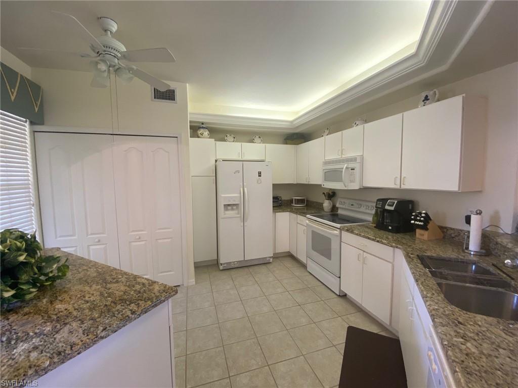 a kitchen with stainless steel appliances granite countertop a refrigerator sink and white cabinets