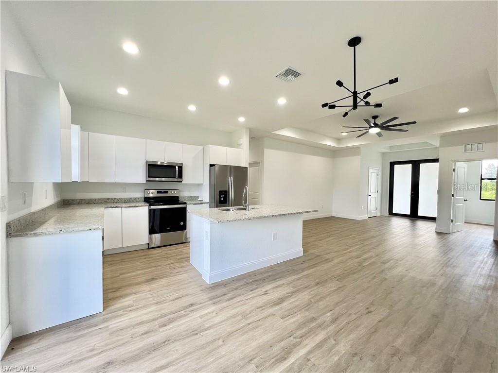 a large kitchen with stainless steel appliances kitchen island a large counter top a stove and a wooden floors