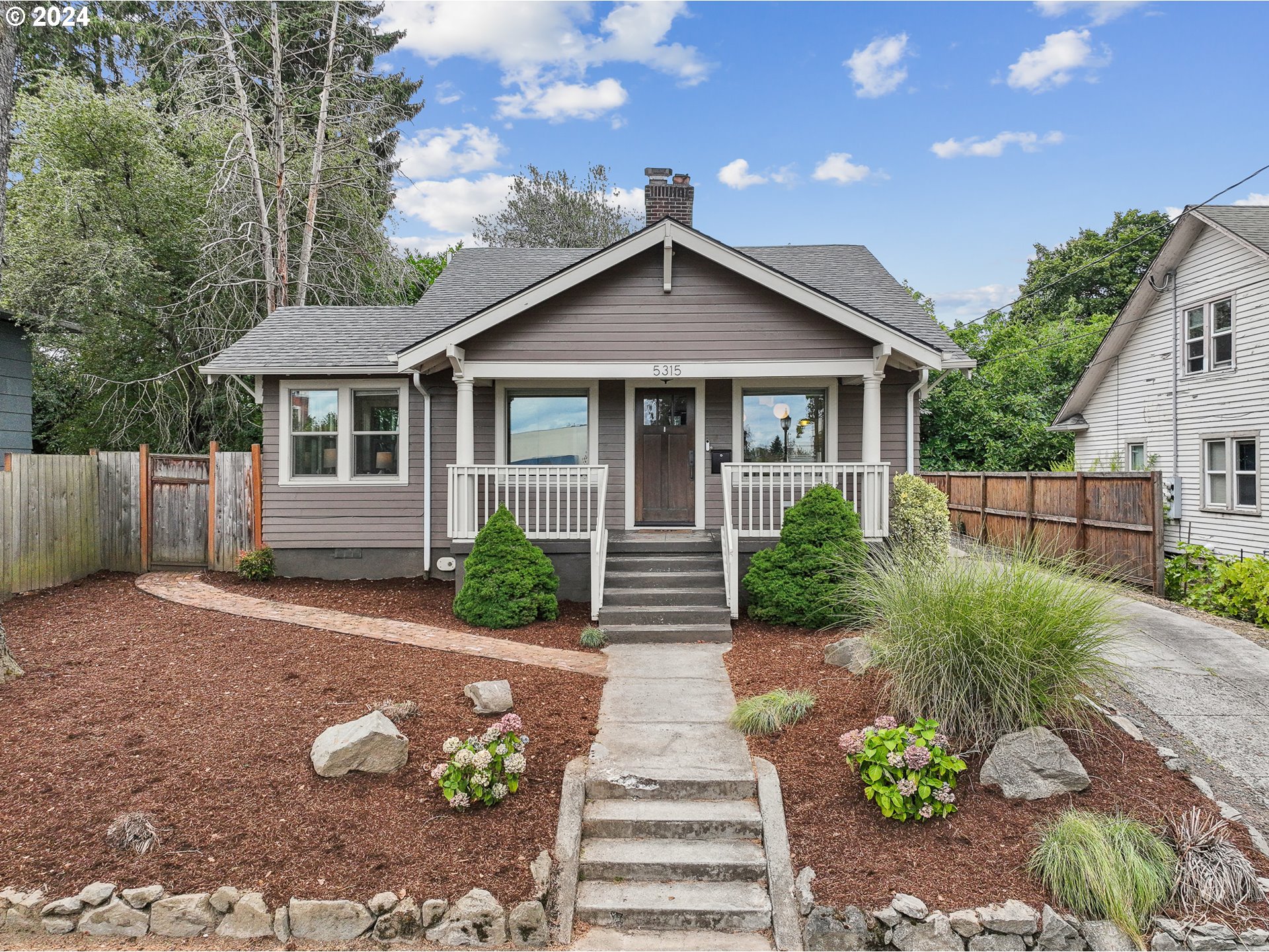 a front view of a house with a yard and potted plants