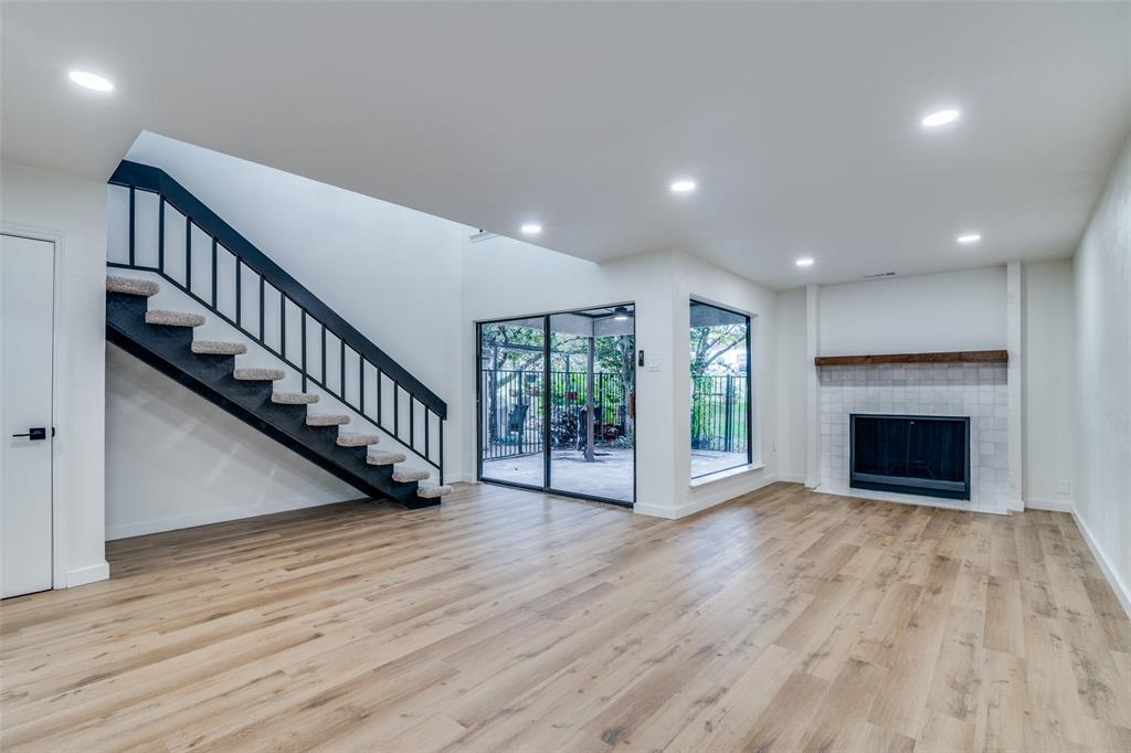 a view of an empty room with wooden floor a fireplace and a window