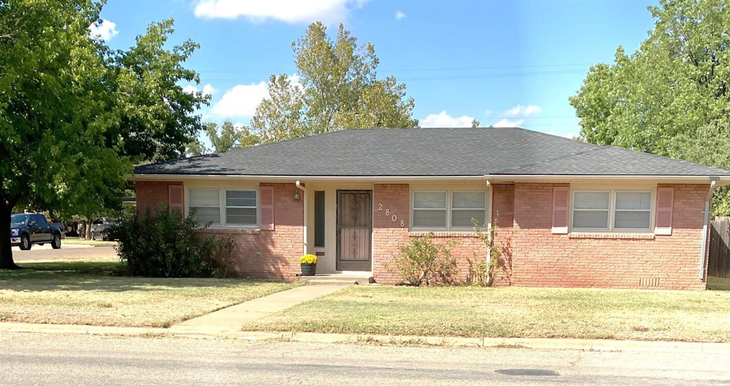 a front view of a house with a garden and tree