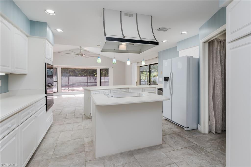 a kitchen with stainless steel appliances kitchen island granite countertop a refrigerator and a sink