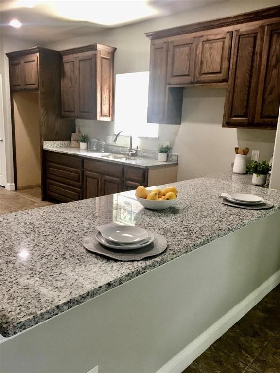 a kitchen with kitchen island granite countertop a sink a stove and cabinets