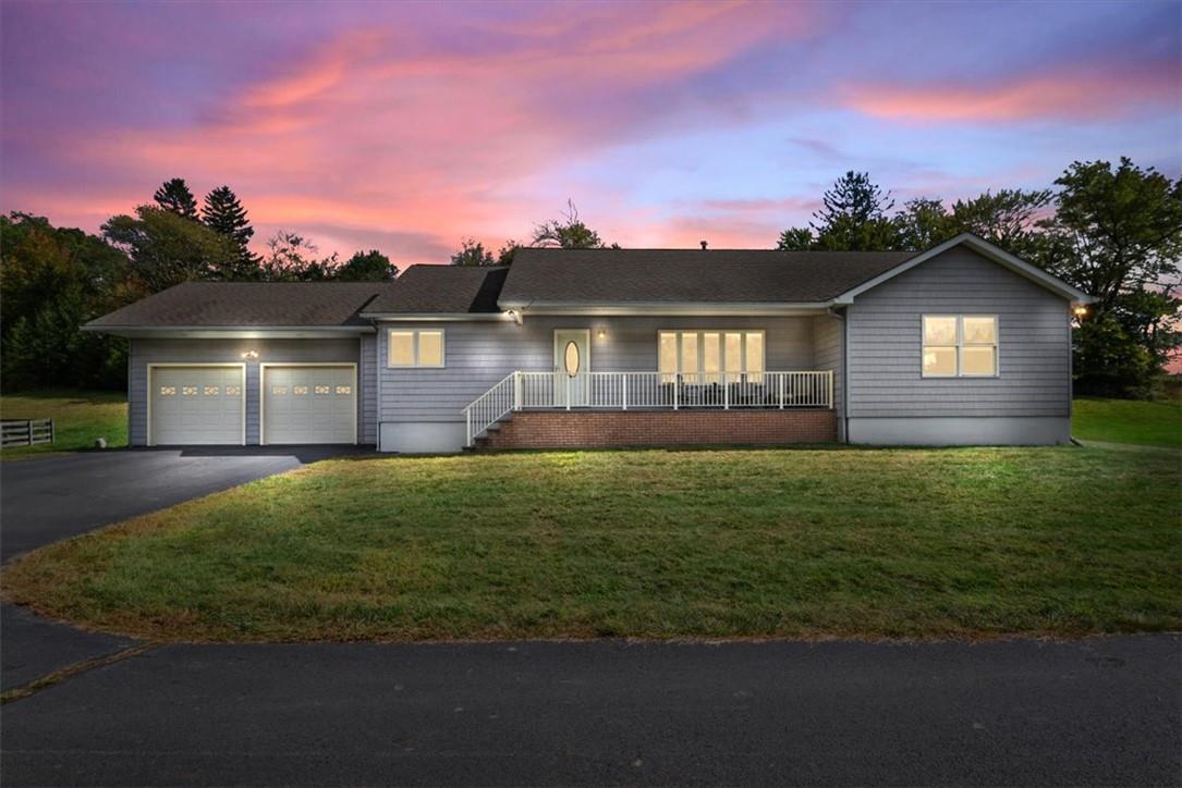 Single story home with a garage, a lawn, and covered porch