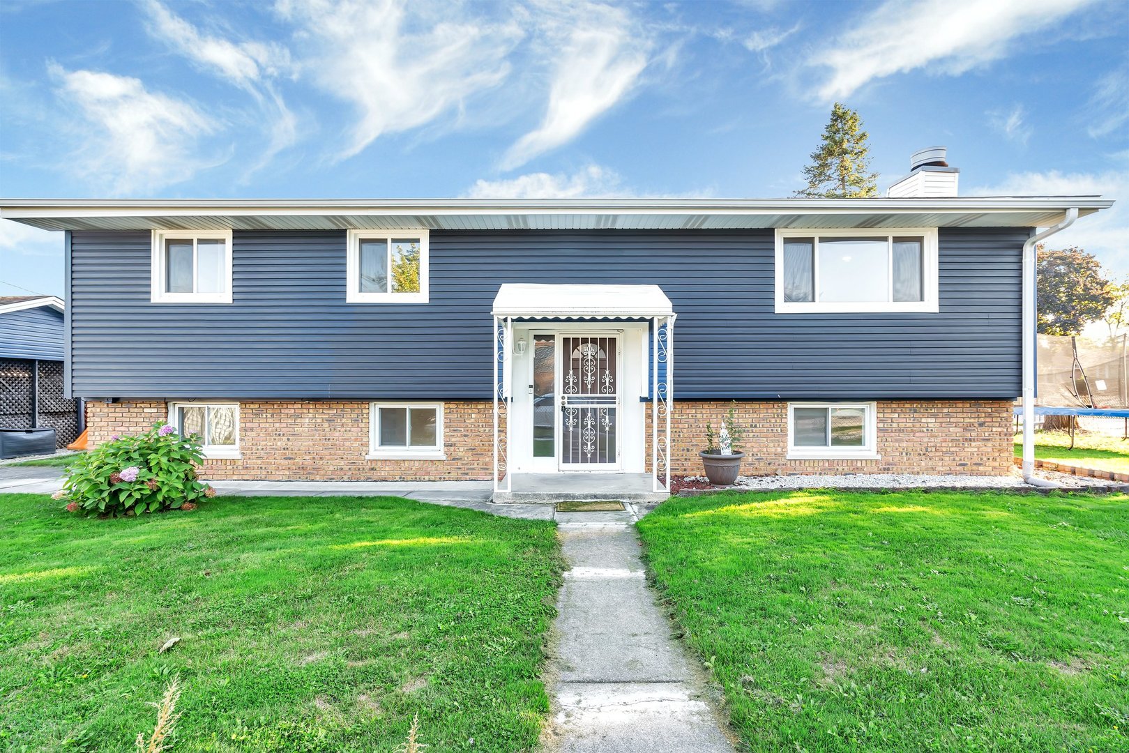 a front view of a house with a yard and green space